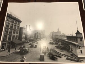 A black and white photo of an intersection with cars driving on it.