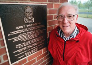 A man standing next to a plaque with an image of john t. Jack griffin on it