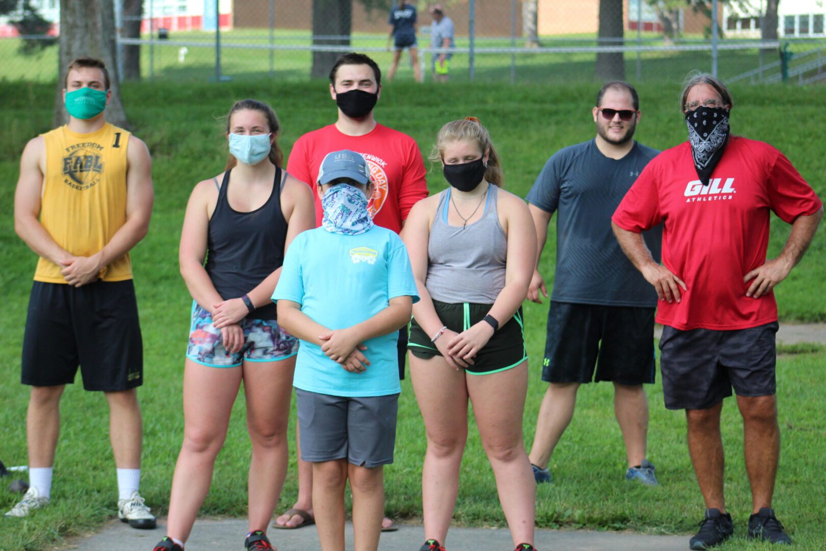 A group of people standing in the grass wearing masks.