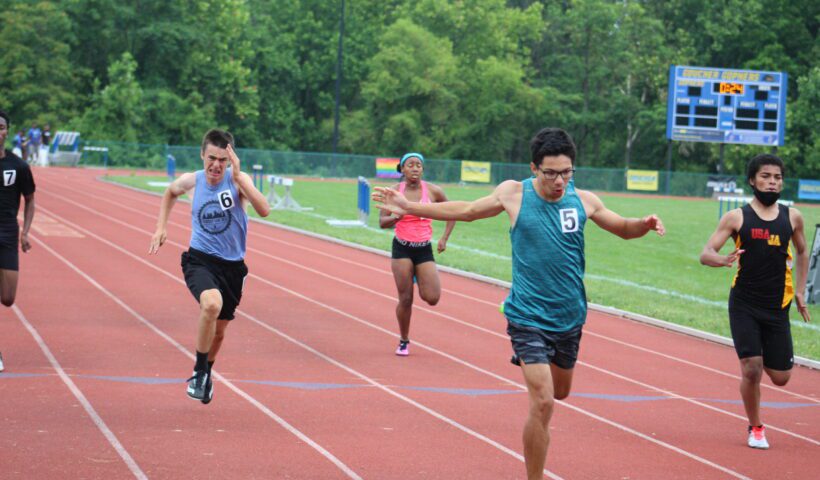 Three people running on a track in the middle of a race.