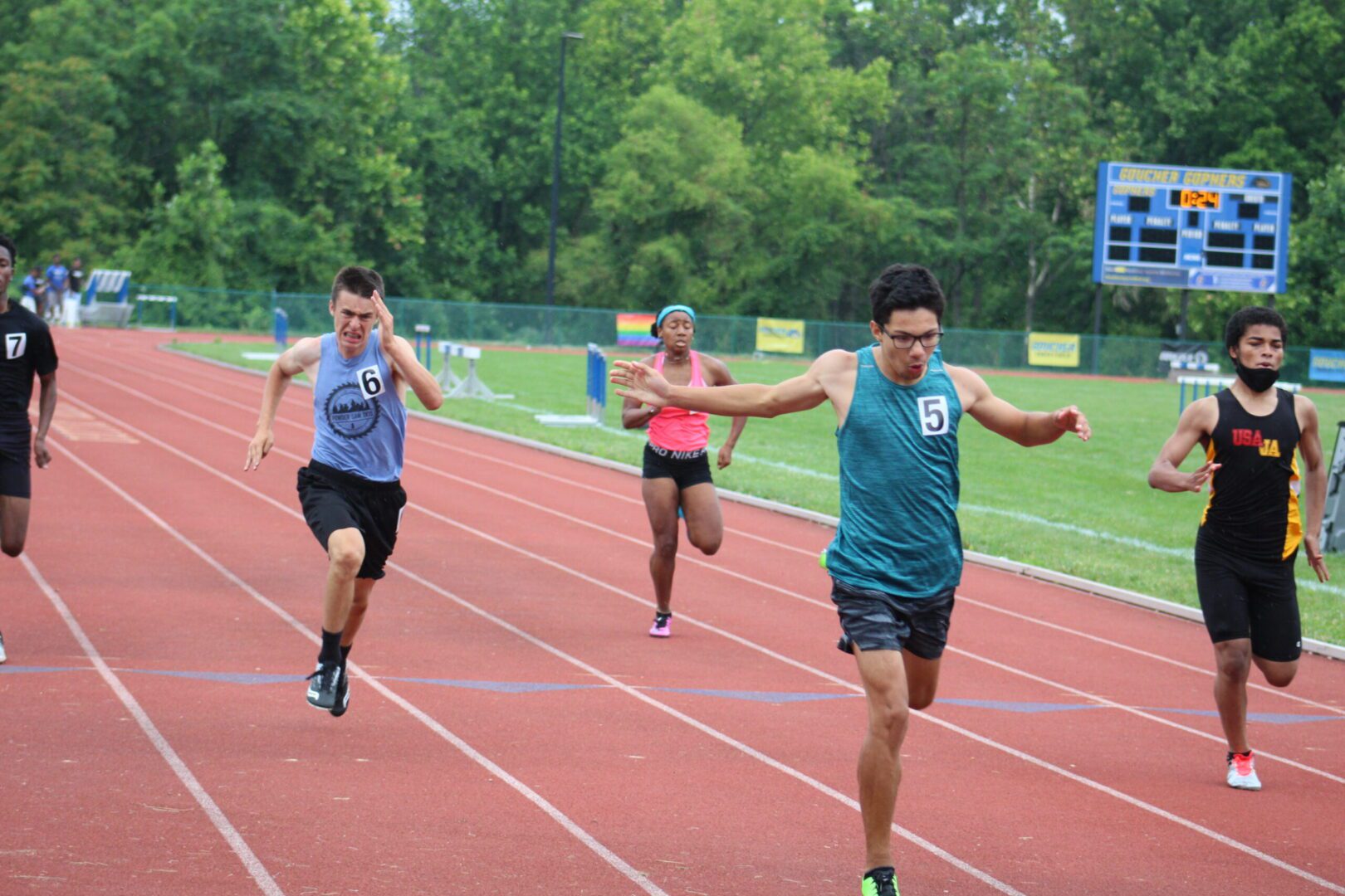 Three people running on a track in the middle of a race.