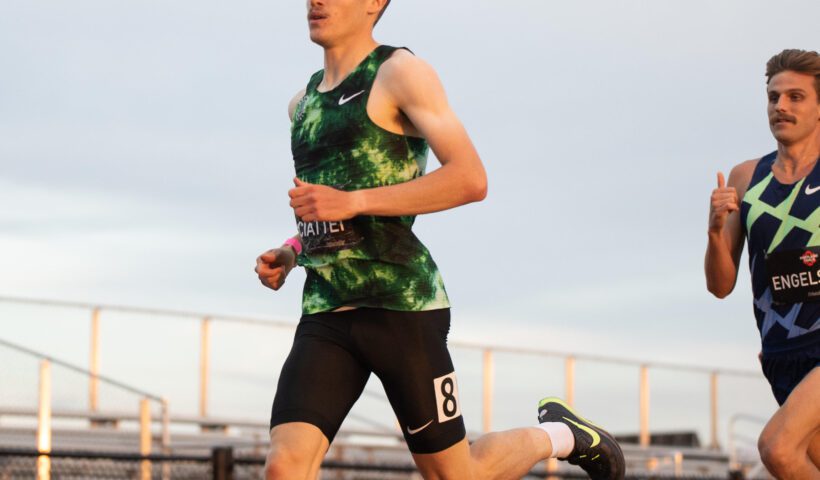 A man running on the track in a green shirt