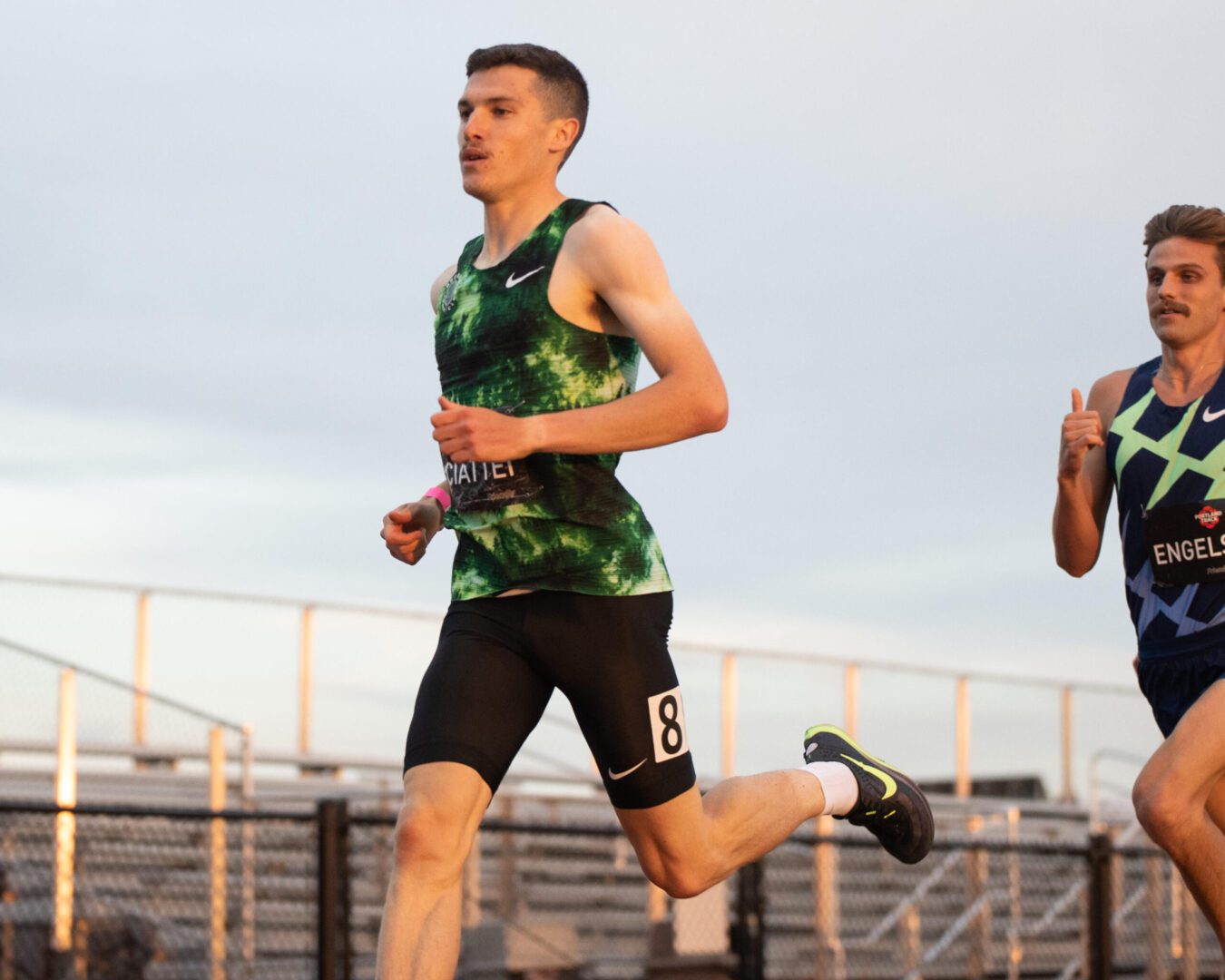 A man running on the track in a green shirt