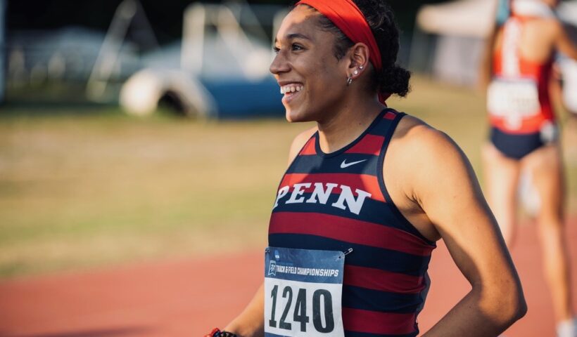 A woman running on the track with a race number.