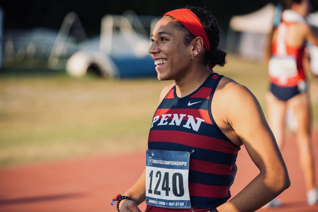 A woman running on the track with a race number.