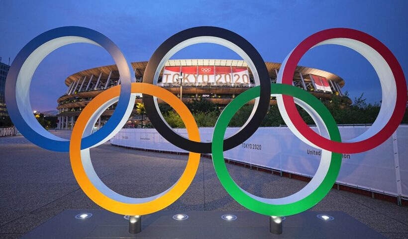 A group of olympic rings sitting in front of an arena.