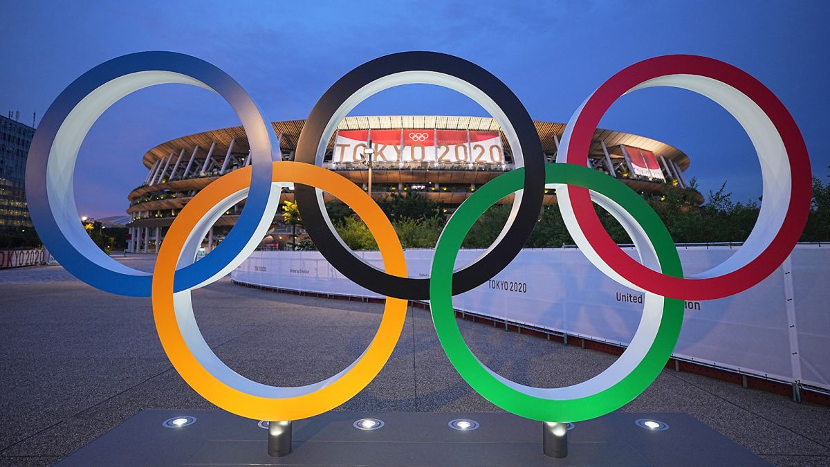 A group of olympic rings sitting in front of an arena.