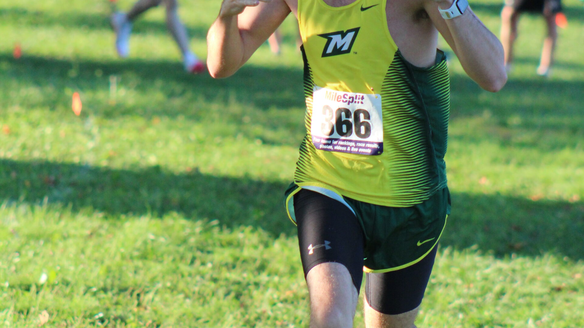 A man running in the grass with his thumb up.