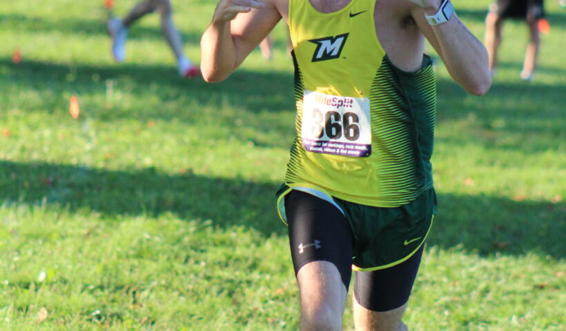 A man running in the grass with his thumb up.