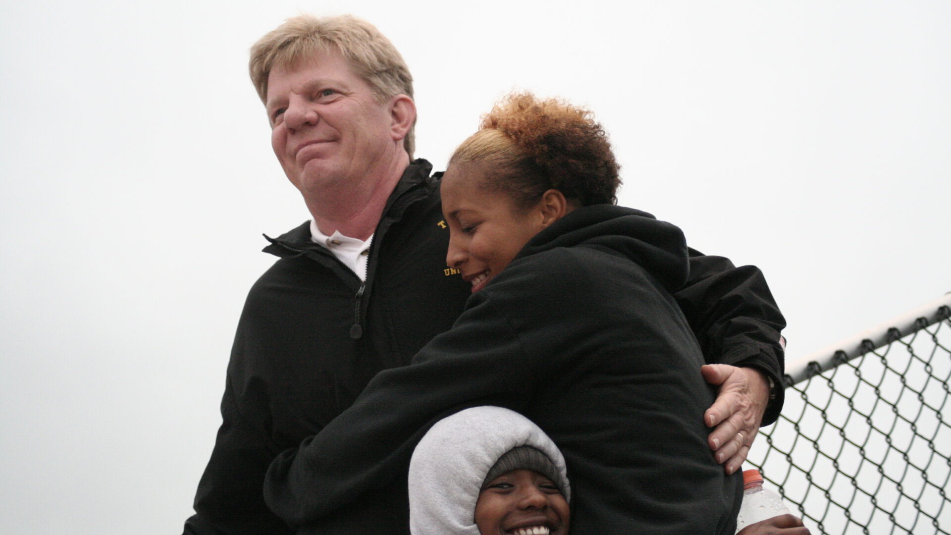 A man and two women hugging each other.