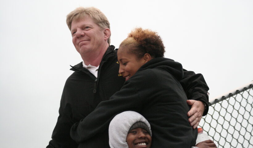 A man and two women hugging each other.