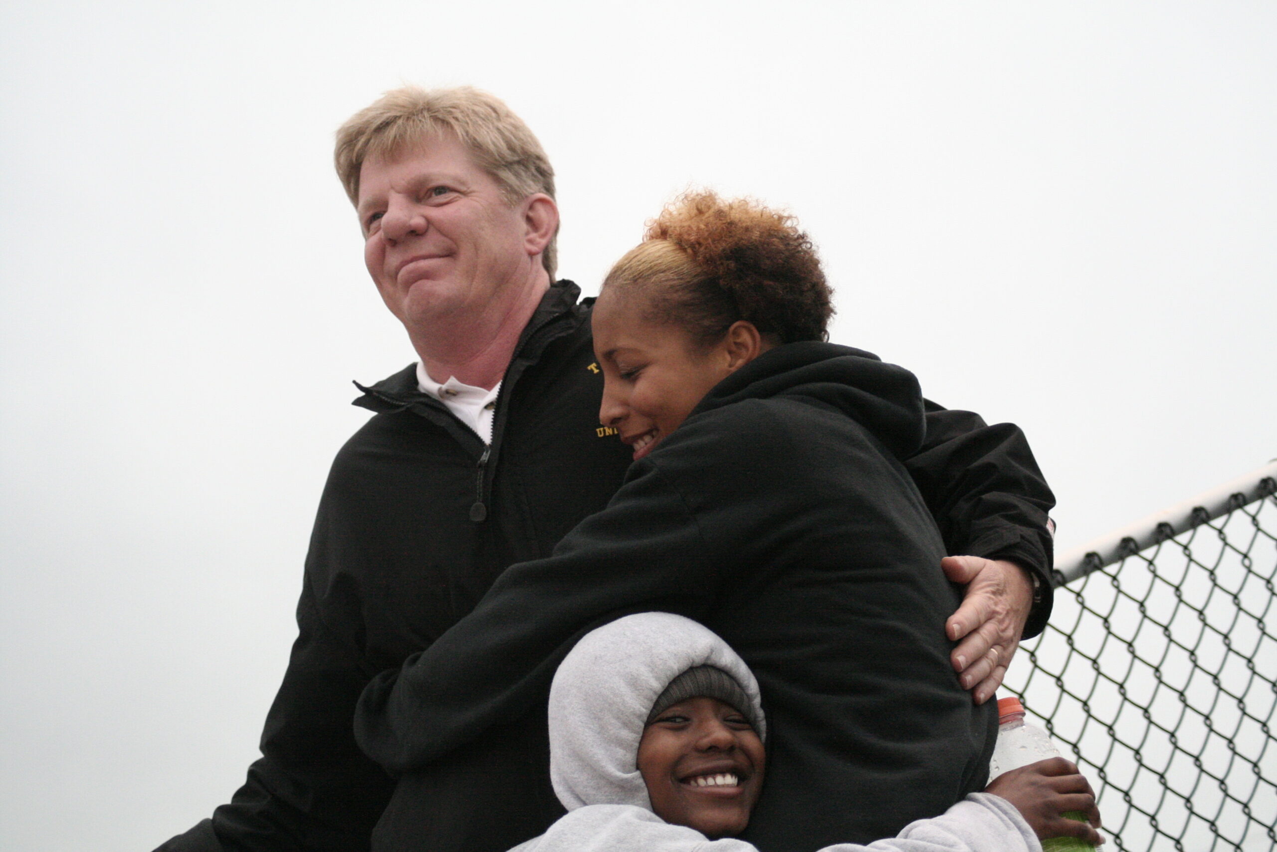 A man and two women hugging each other.