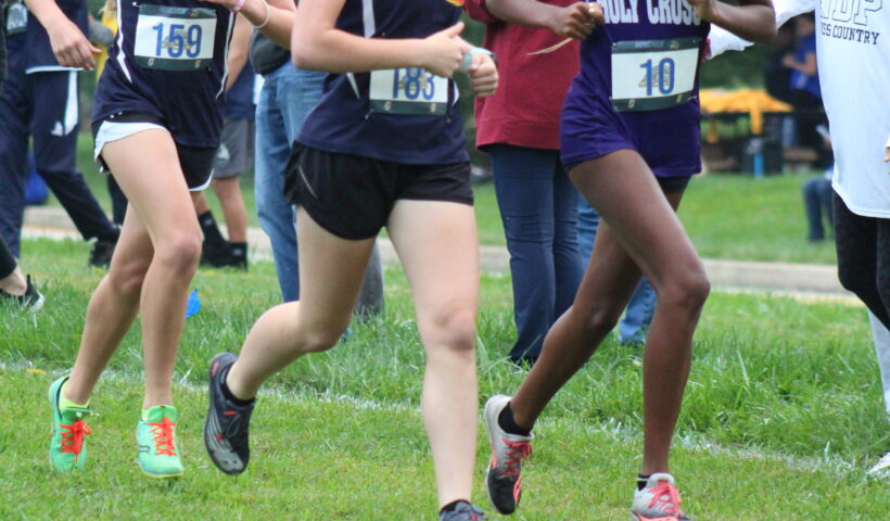 A group of young people running on the grass.