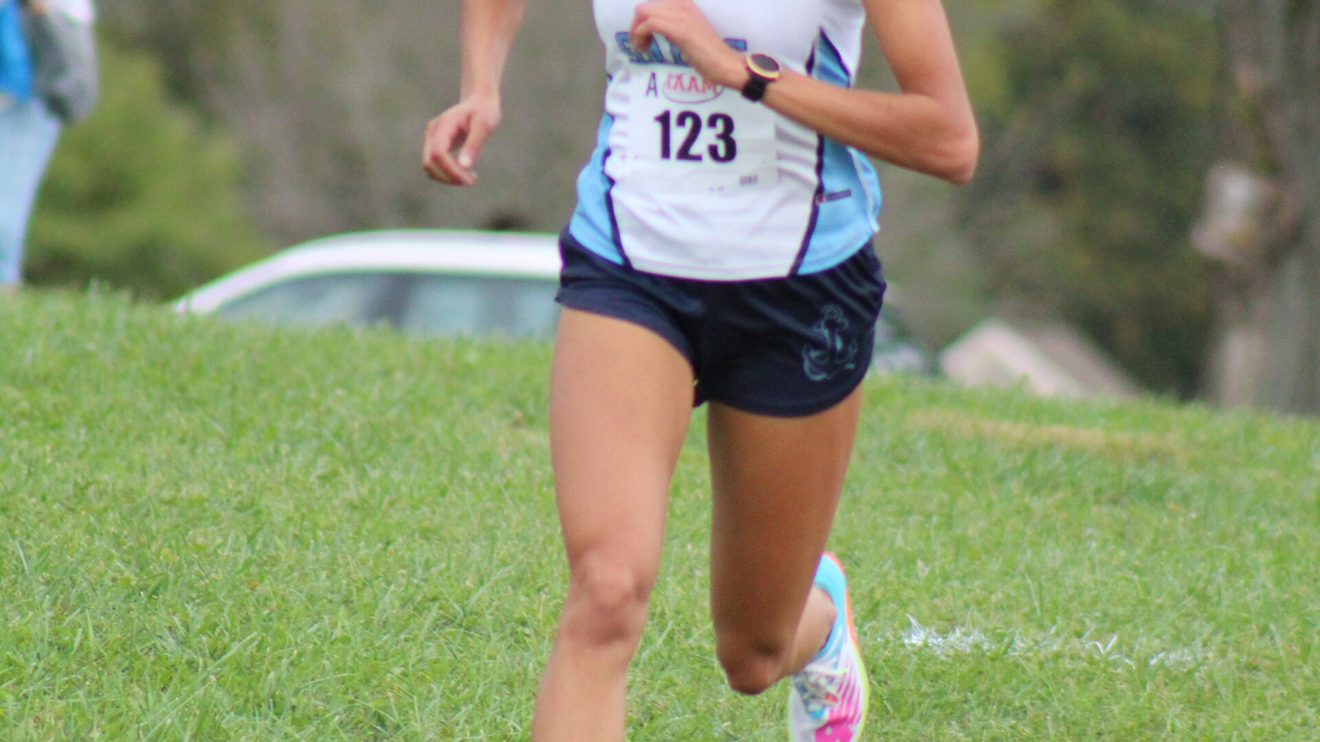 A woman running on the grass in a race.