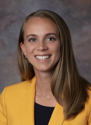 A woman in a yellow jacket smiling for the camera.