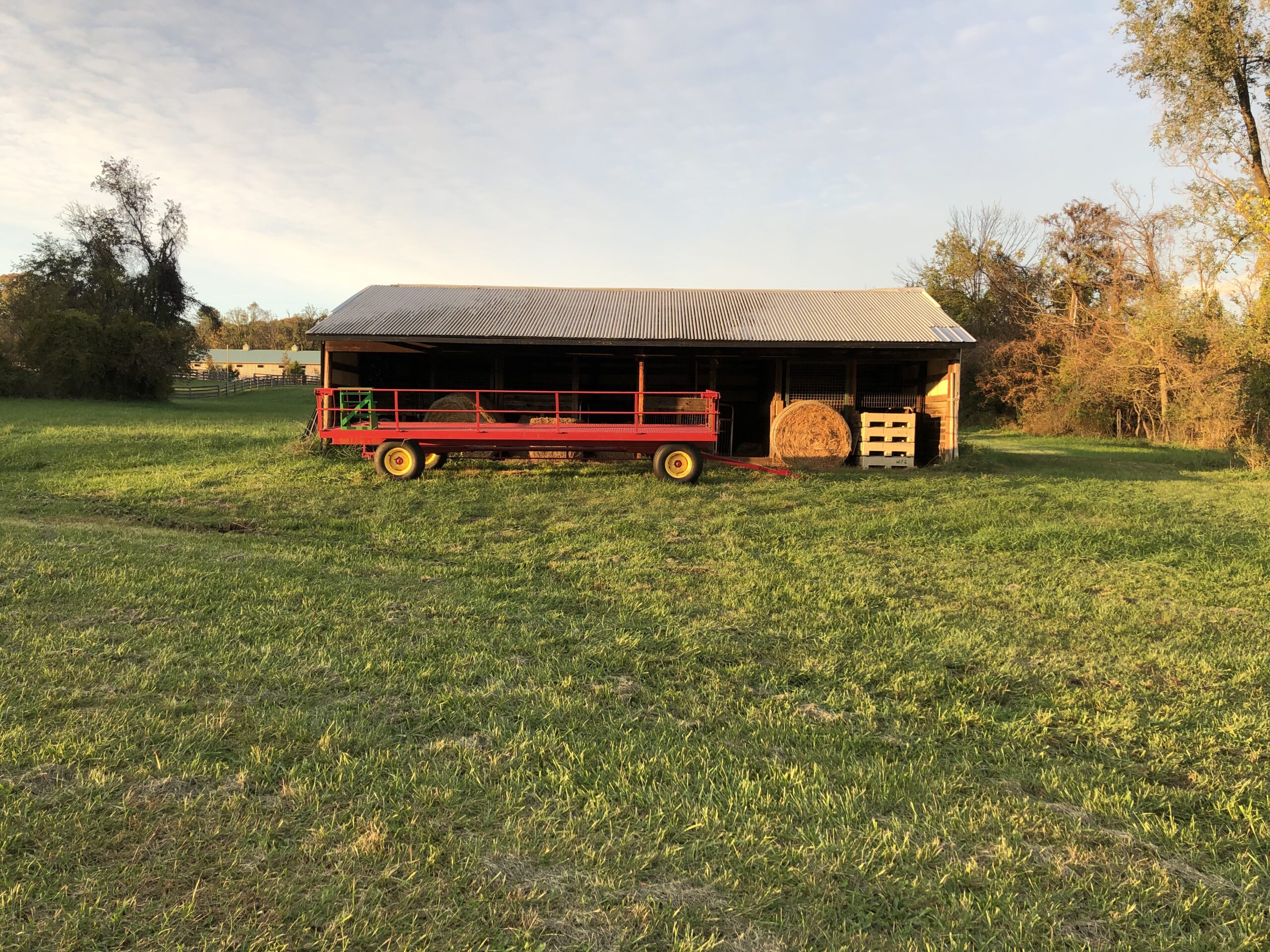 A red truck parked in front of a barn.