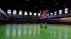A large indoor arena with green floor and american flag.