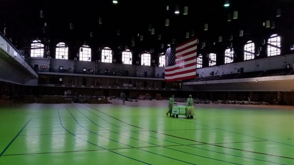 A large indoor arena with green floor and american flag.