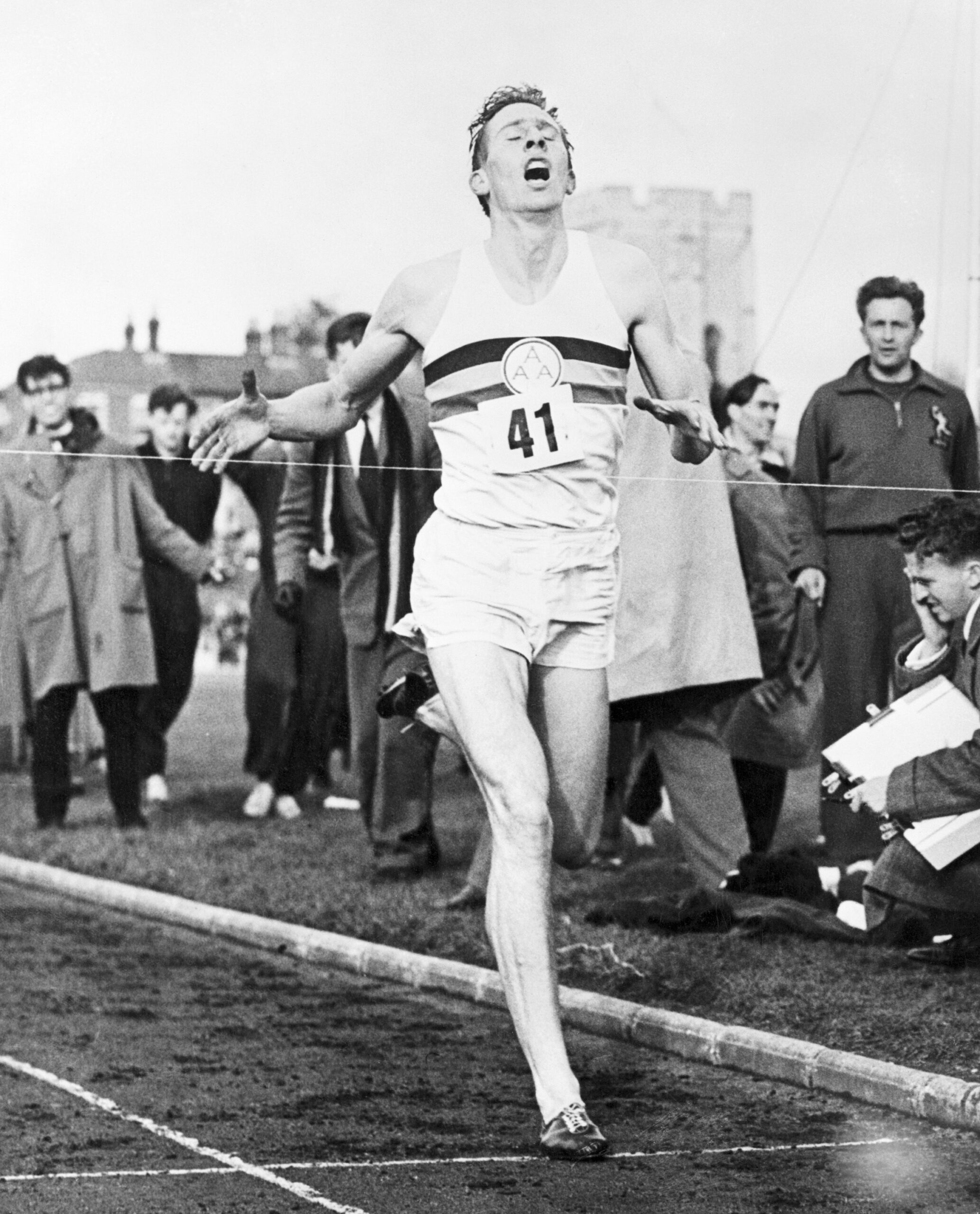 A man running on the track with people watching.