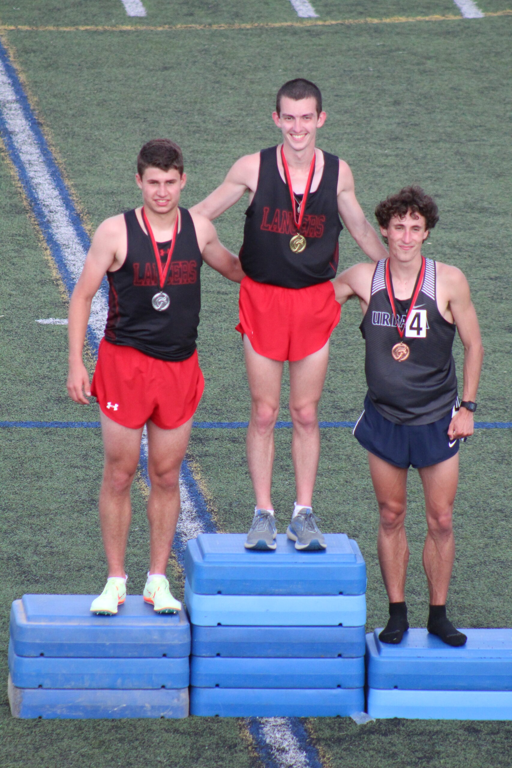 Three men standing on a platform with medals around their necks.