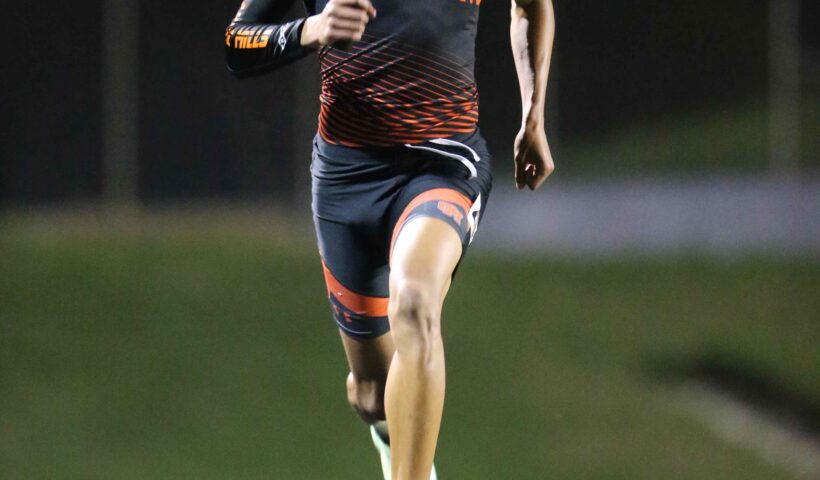 A man running on the track at night.