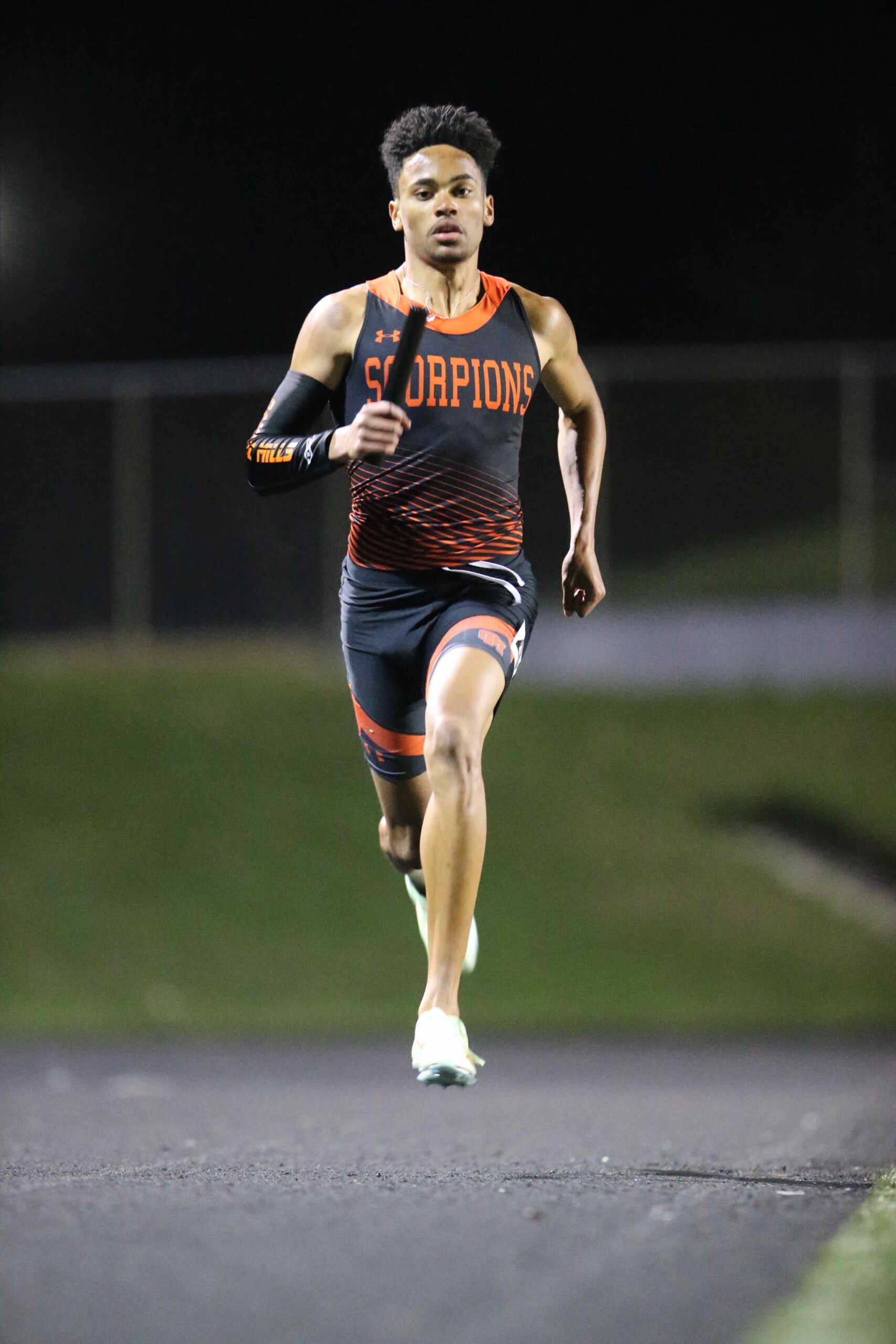 A man running on the track at night.