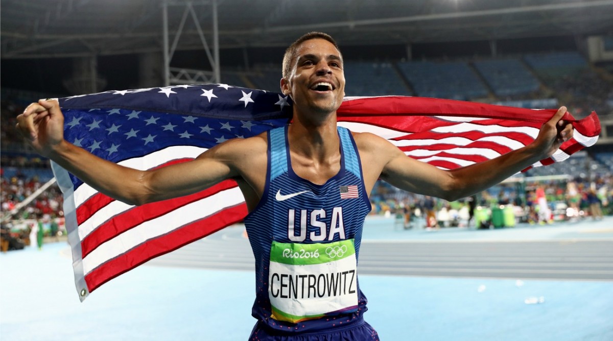 A man is holding an american flag and smiling.