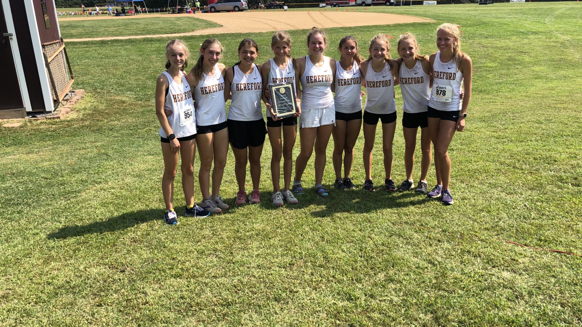 A group of girls standing on top of a grass covered field.