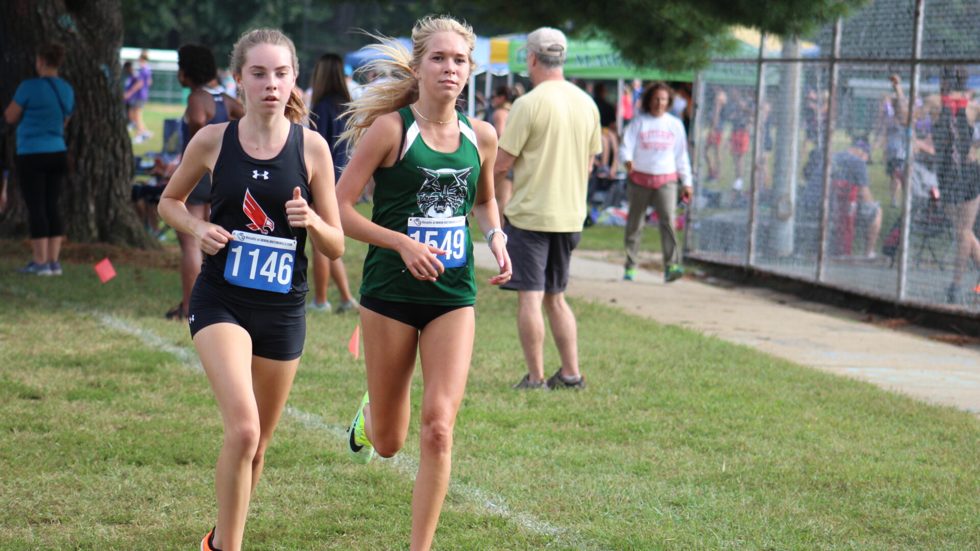 Two girls running in a cross country race.