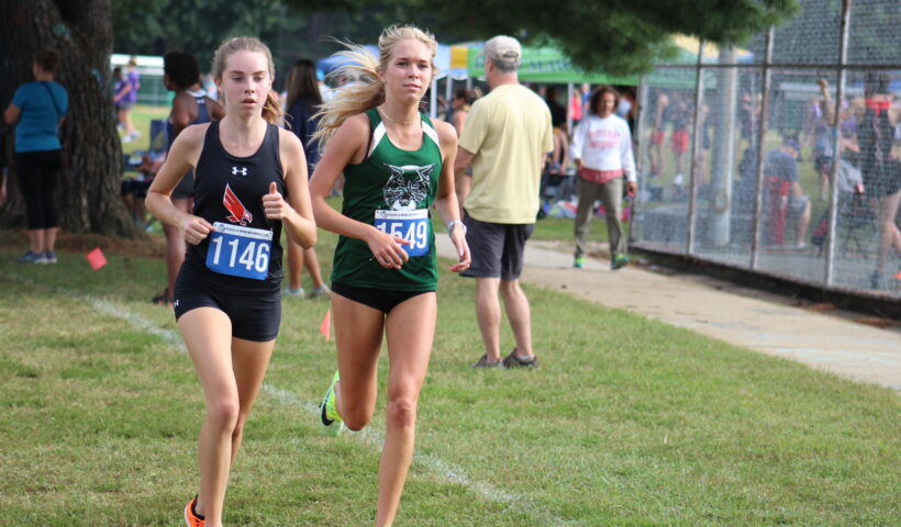 Two girls running in a cross country race.