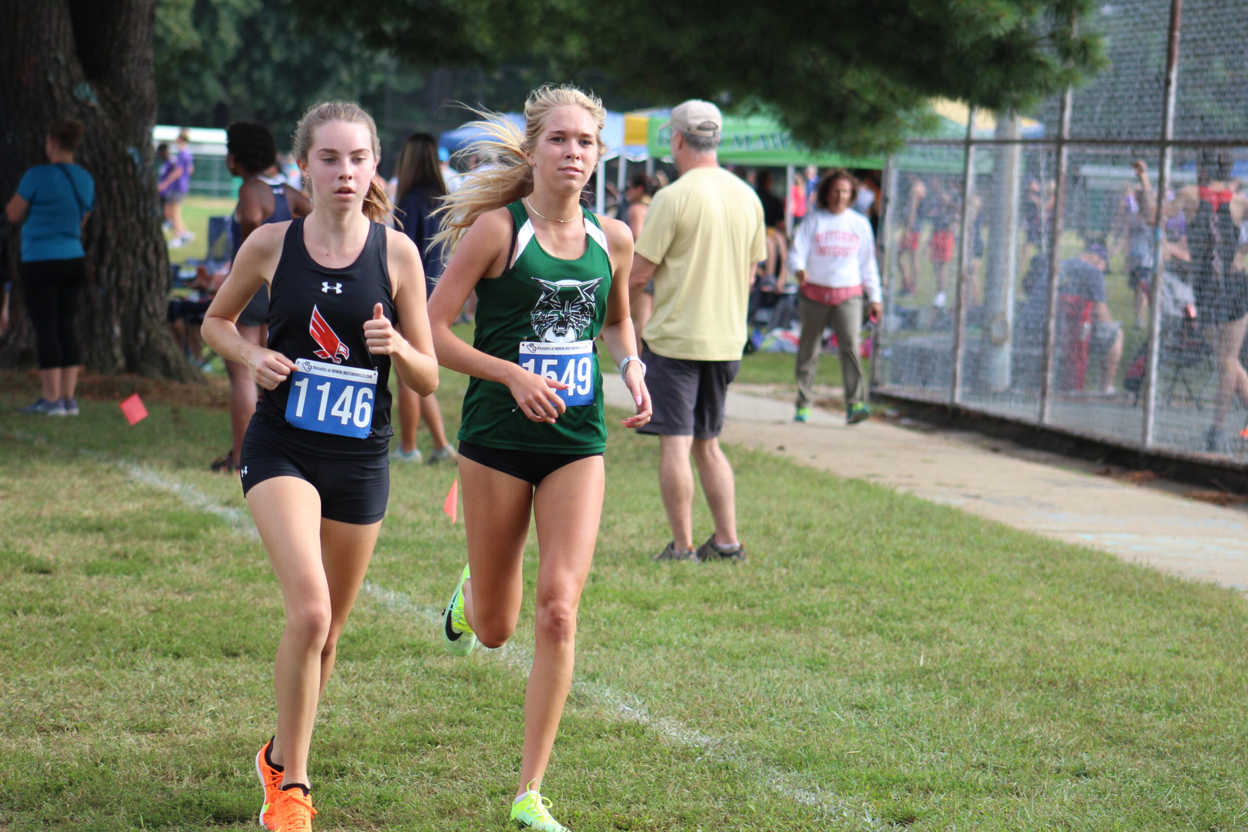 Two girls running in a cross country race.