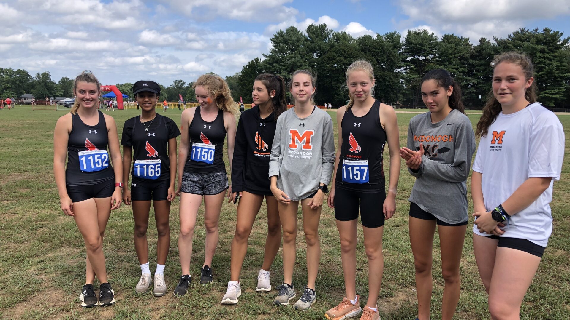 A group of girls standing in the grass.