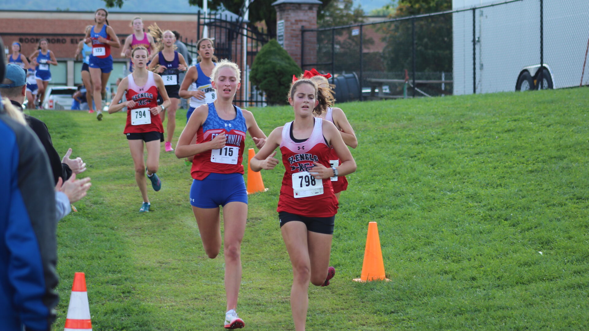 A group of young girls running in the grass.