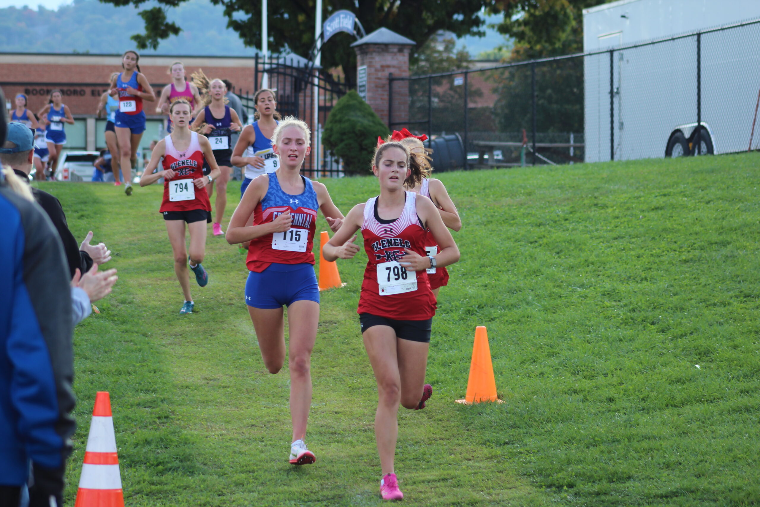 A group of young girls running in the grass.