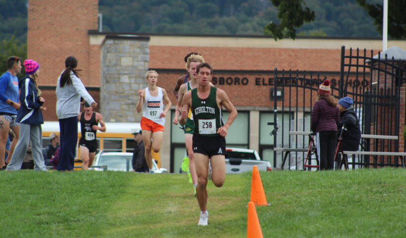 A person running in the grass near orange cones.