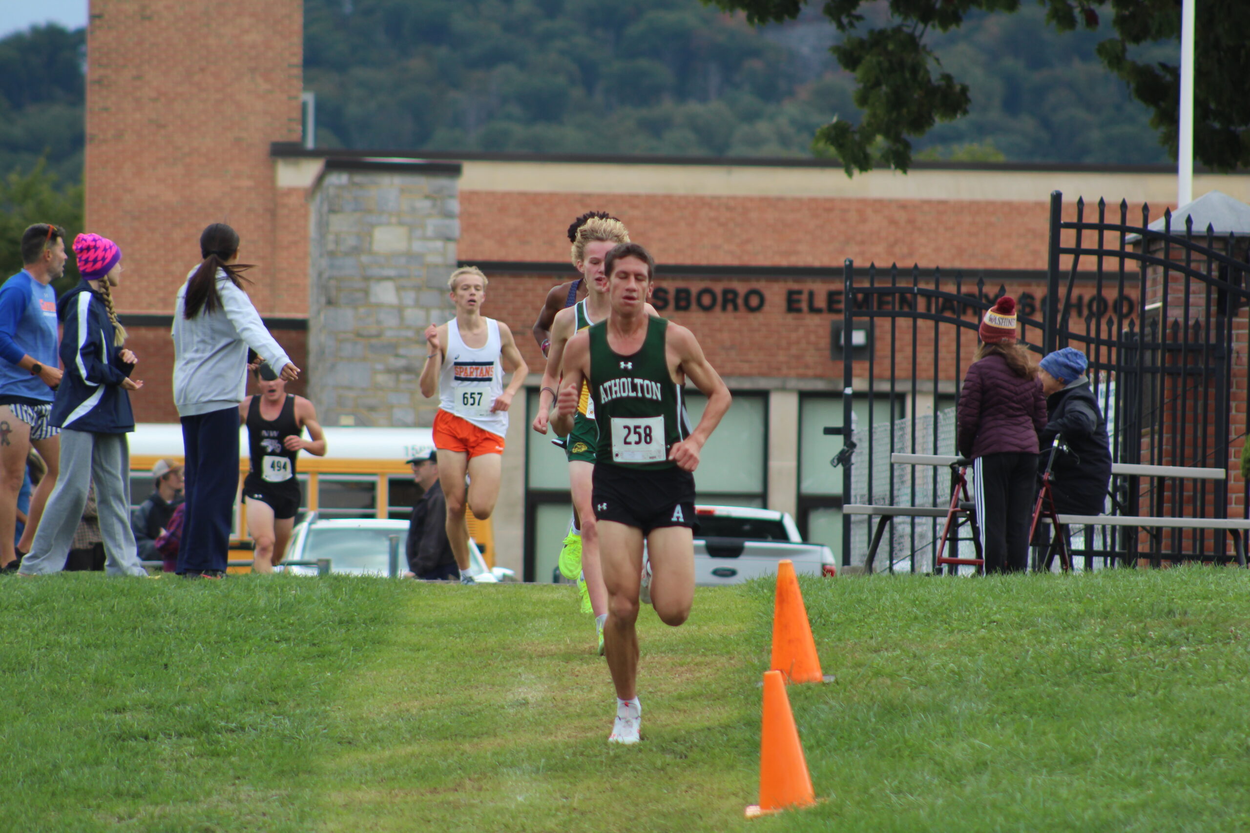 A person running in the grass near orange cones.