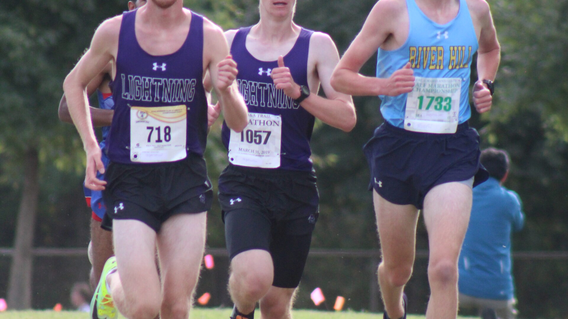 Three men running in a cross country race.