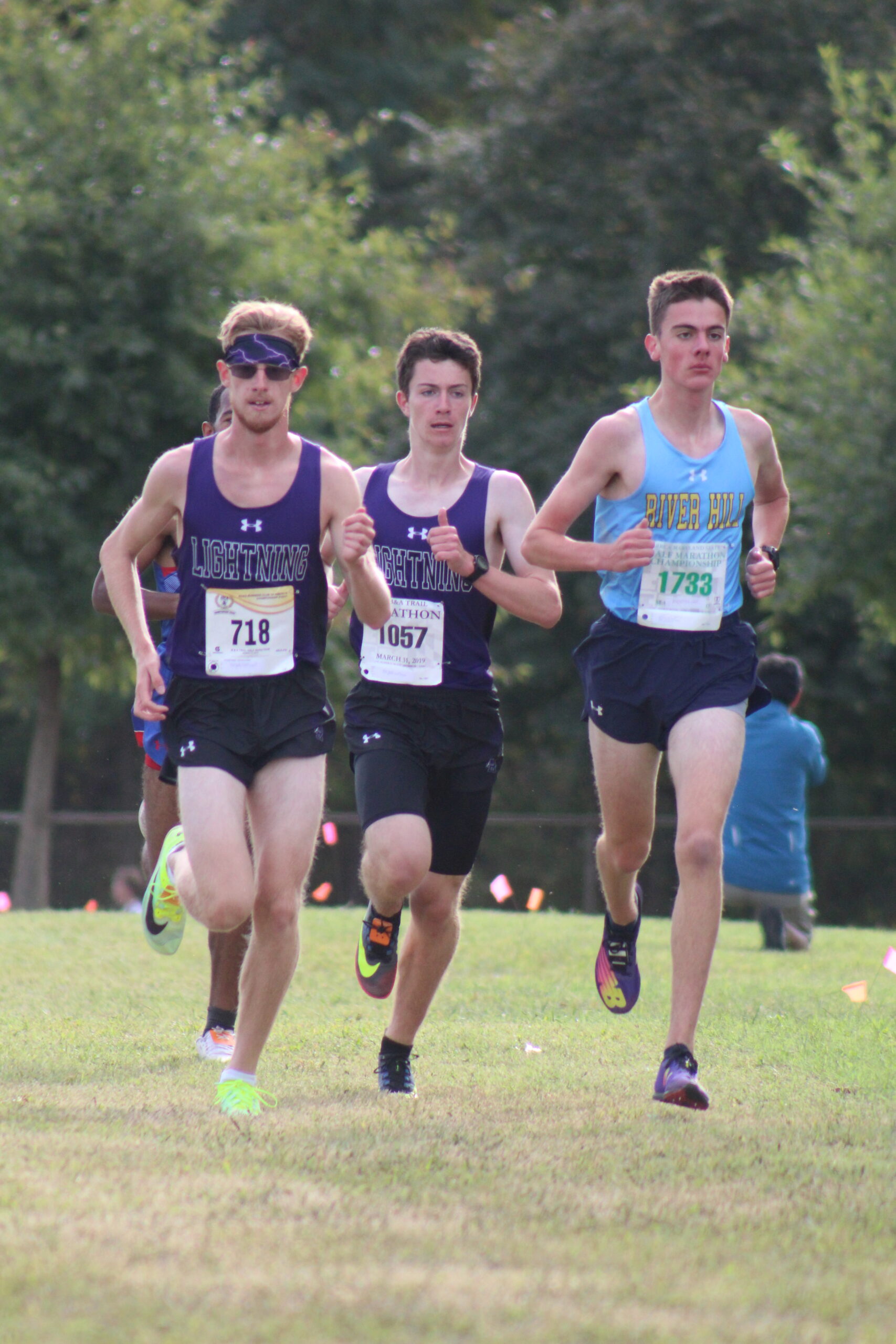 Three men running in a cross country race.