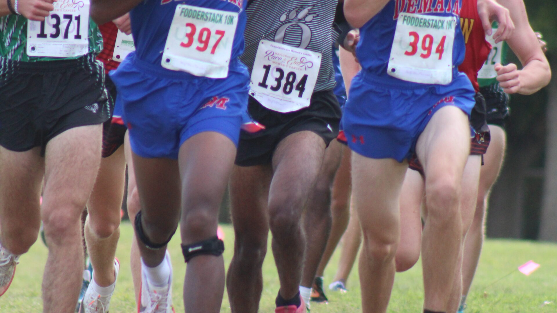A group of men running in the grass.