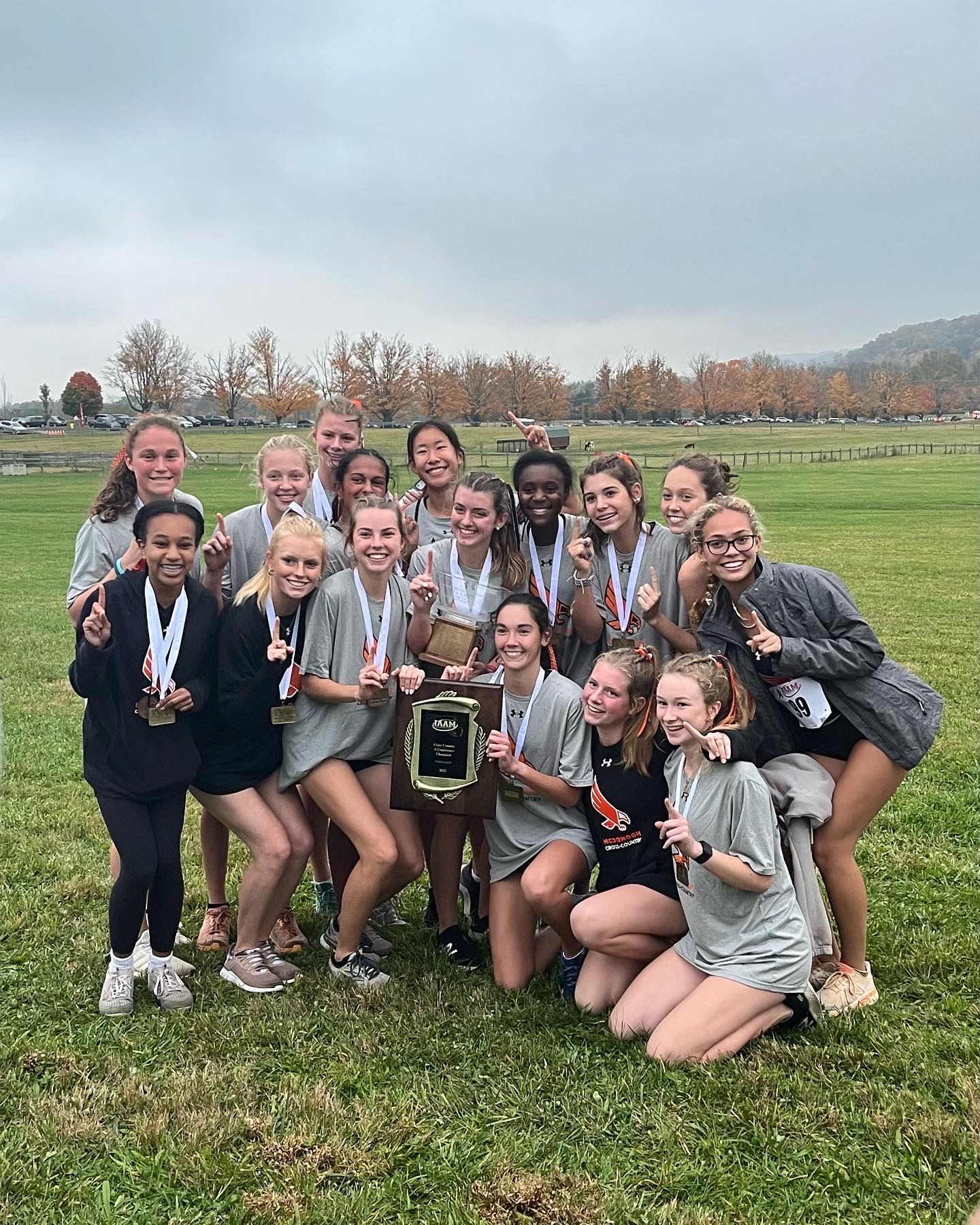 A group of girls standing in the grass holding medals.