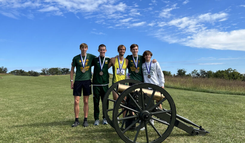 A group of people standing in the grass with medals around their necks.