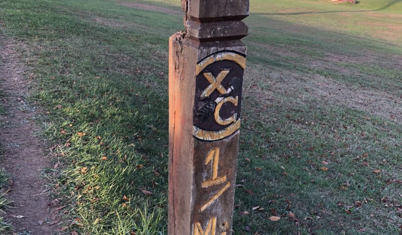 A wooden post with the initials xc and 1 m on it.