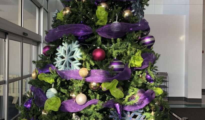 A christmas tree with purple decorations and green leaves.