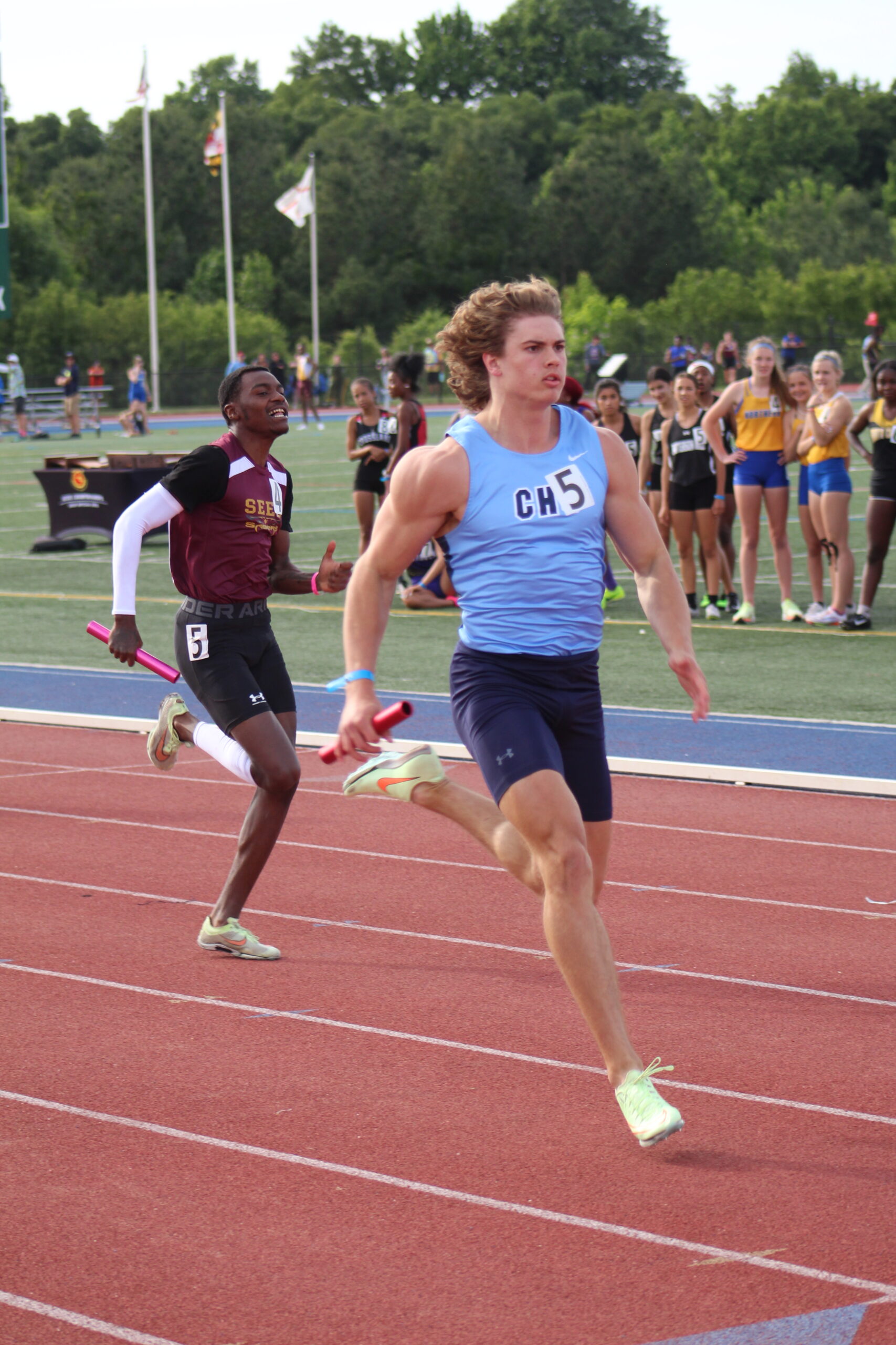 A man running on the track while holding a tennis racket.