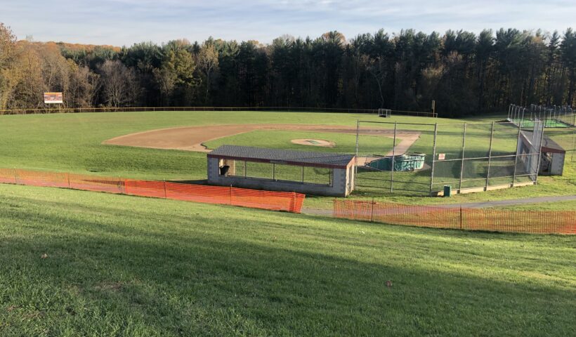 A baseball field with a bench and a fence.