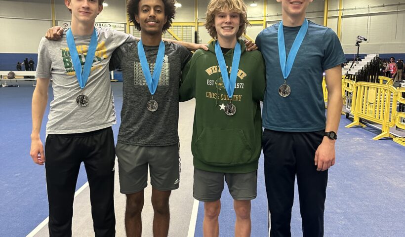 Four boys standing next to each other with medals around their necks.